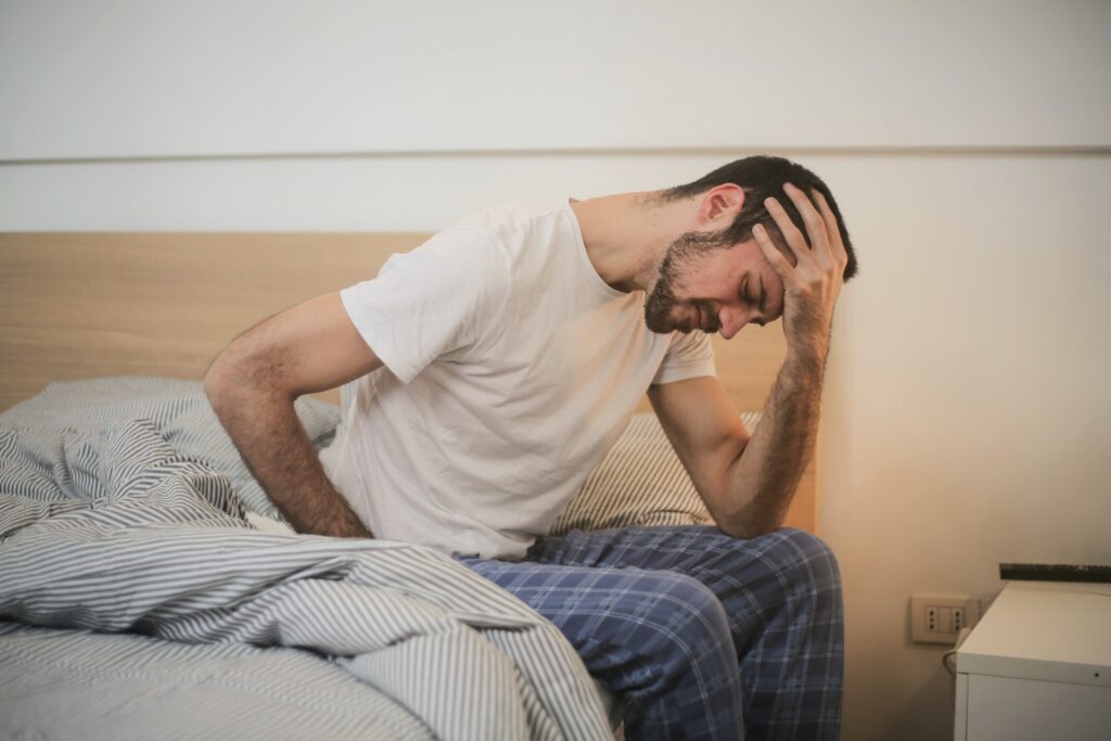 stressed man sitting on the bed holding his head
