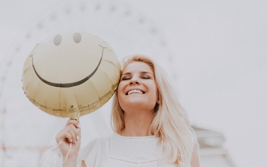 Happy woman smiling with a smiley face balloon
