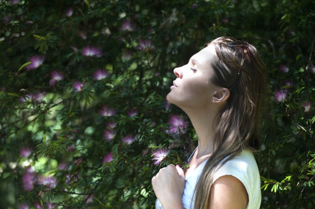 woman meditating outside holding a flower