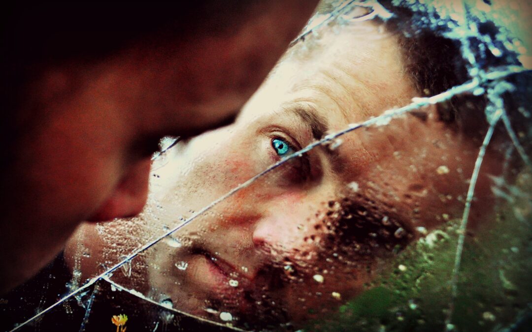 man looking at himself in a broken mirror