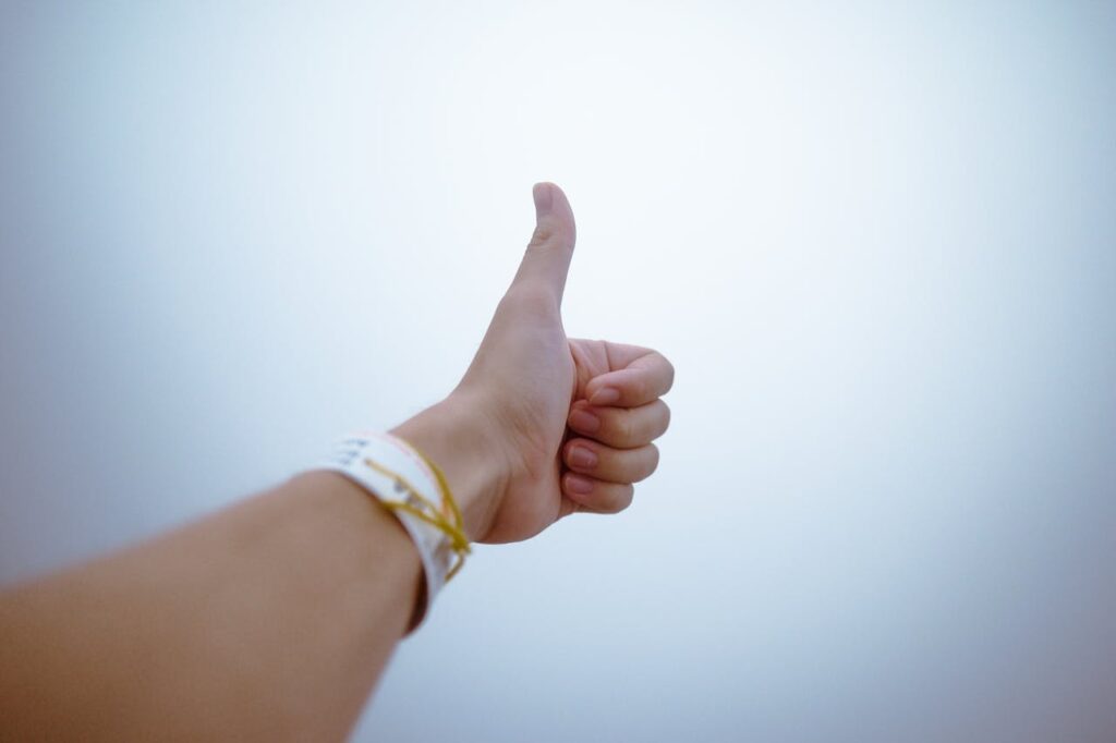 a hand showing thumbs up as a symbol of positivity